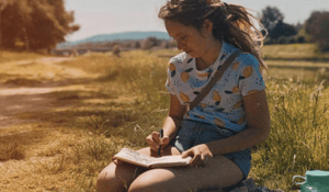 Woman in field with sketchbook drawing yellow lemon shirt